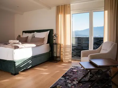 a bedroom with a bed and a chair and a window at PENTHOUSE ROYA BiHAC in Bihać