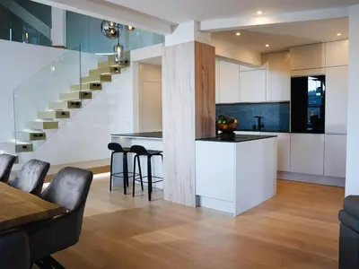 a kitchen and dining area with a staircase in a house at PENTHOUSE ROYA BiHAC in Bihać