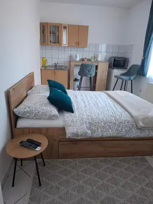 a bedroom with a bed with blue pillows and a table at Studio apartman KONAK in Kupres