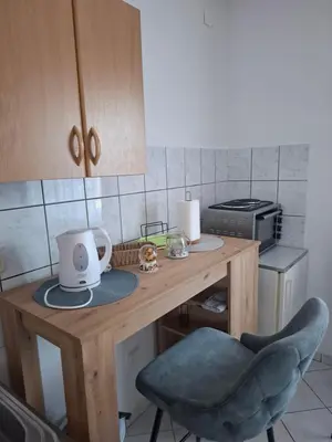 a small kitchen with a wooden table with a chair at Studio apartman KONAK in Kupres