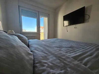 a bedroom with a bed and a flat screen tv at City Place Apartment in Banja Luka