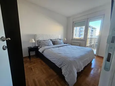 a bedroom with a bed and a large window at City Place Apartment in Banja Luka