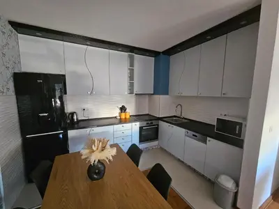 a kitchen with a wooden table and white cabinets at City Place Apartment in Banja Luka