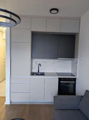 a kitchen with white cabinets and a sink and a couch at Triton in Banja Luka
