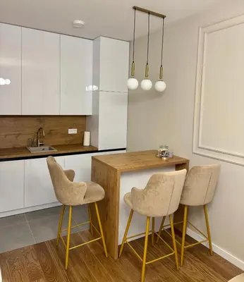 a kitchen with white cabinets and a wooden table and chairs at Apartman GrandTrade by Termax in Banja Luka