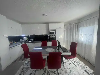 a kitchen with a dining table and red chairs at Zanesovici Jezero in Bugojno