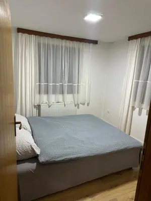 a bedroom with a bed and a window with white curtains at Apartman Nina in Šišava