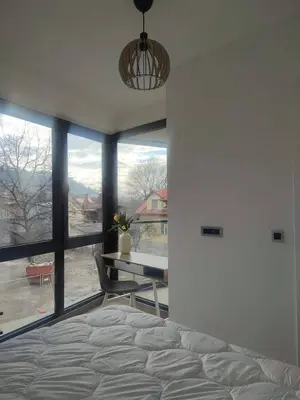 a bedroom with a bed and a table and a window at Banja Residence Apt in Tuzla