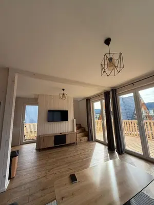 a living room with a television and large windows at Vlasic Odmor - Villa Amina in Vlasic