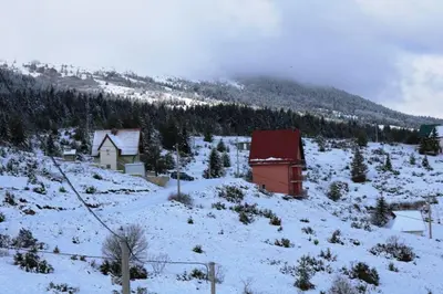 a snow covered hillside with a small building on it at Apartmani Ciro in Kupres