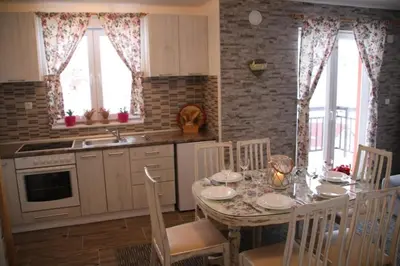 a kitchen with a table and chairs and a kitchen with a sink at Apartmani Ciro in Kupres