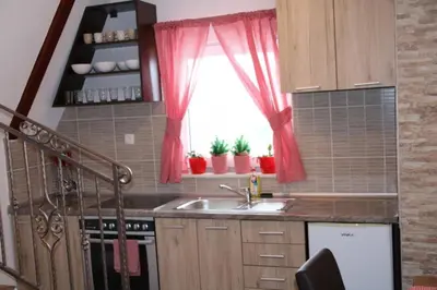 a kitchen with a sink and a window with red curtains at Apartmani Ciro in Kupres