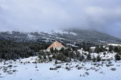 a building on top of a snow covered mountain at Apartmani Ciro in Kupres