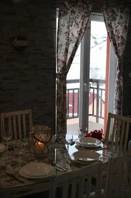 a dining room table with a candle and a window at Apartmani Ciro in Kupres