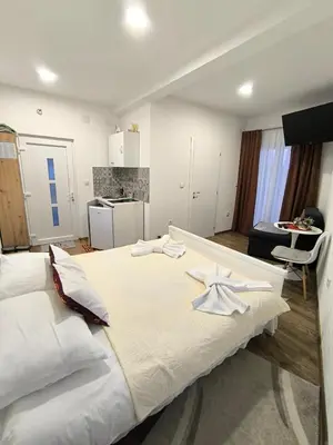 a large white bed in a room with a kitchen at TOKIs apartmani in Mrkonjić Grad