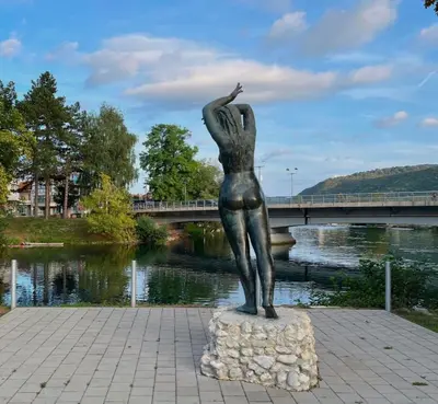 a statue of a woman standing on a rock next to a river at Apartman Mila in Bihać