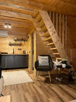 a living room with a staircase in a wooden cabin at Cottage Soul Rest