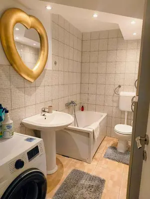 a bathroom with a sink and a toilet and a washing machine at City Center Apartment in Banja Luka