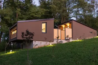 a small house on a hill with lights on it at BLOK Wood Cottage in Ivišovo Greblje