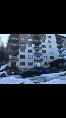 a parking lot with cars parked in front of a building at Apartment Snow Vlašić in Šišava
