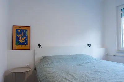 a white bedroom with a bed and a table at Apartman Srna in Banja Luka