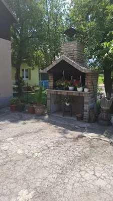 a brick fireplace with potted plants in a yard at Apartman - TAHRIC in Bihać