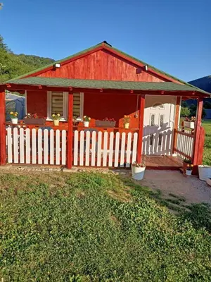 a red house with a white fence in front of it at Mubina Apartman in Ćukovi