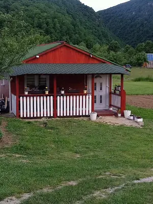 a red house with a white fence in a field at Mubina Apartman in Ćukovi