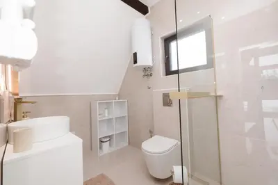 a white bathroom with a toilet and a window at De Villa Bey in Kupres