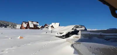 a snow covered car parked in a snow covered village at Vikendica Jadranka in Kupres