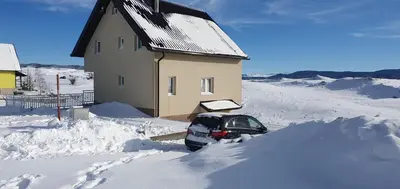 a car buried in snow in front of a house at Vikendica Jadranka in Kupres