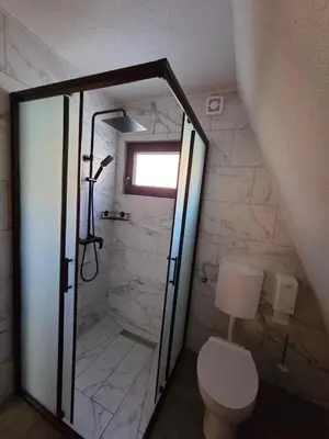 a bathroom with a shower with a toilet and a window at Kozara Resort