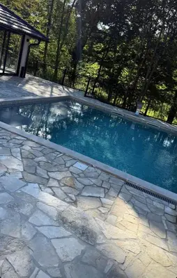 a swimming pool with a stone path around it at Kozara Resort