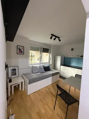 a bedroom with a bed and a table and a kitchen at Welcome Apartment in Banja Luka