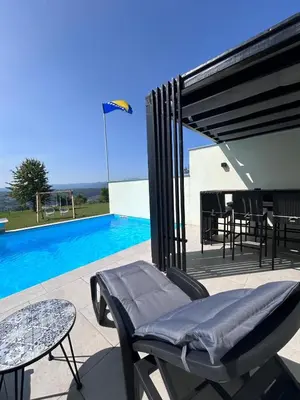 a patio with a table and chairs next to a swimming pool at Villa Sky in Bosanska Krupa