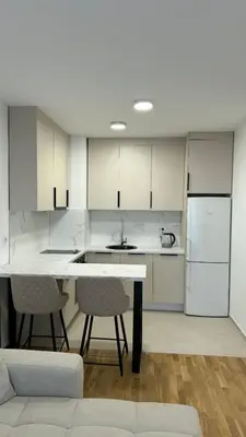 a kitchen with white cabinets and a table and chairs at Stela Stan Na Dan Banja Luka in Banja Luka