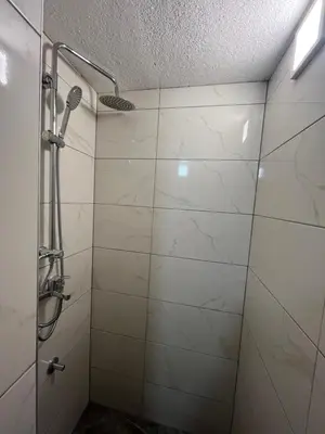 a shower in a bathroom with white tiles at Kuća za odmor Kuna in Kupres