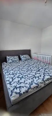a bed with a blue and white comforter on it at Delta in Lukavac