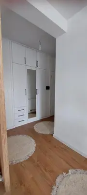 an empty living room with white cabinets and wood floors at Delta in Lukavac