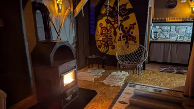 a wood stove in a room with two chairs at Neno Pyramid Wellness Retreat in Visoko