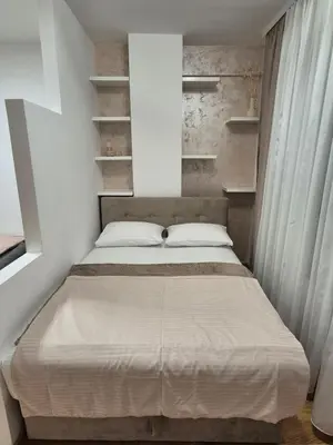 a small bedroom with a bed and shelves at Apartman Silencio 2 in Banja Luka
