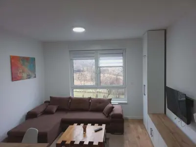 a living room with a brown couch and a table at Apartman Symbol in Tuzla