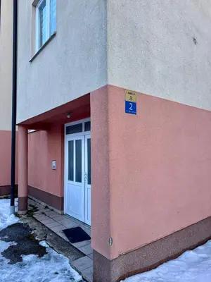 a door to a building with snow on the ground at Apartman Zimski Kutak in Kupres