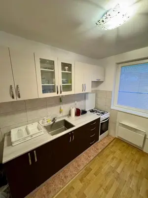 a kitchen with white cabinets and a sink and a window at Apartman Zimski Kutak in Kupres