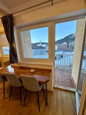 a dining room with a table and a large window at Apartman Zimski Kutak in Kupres