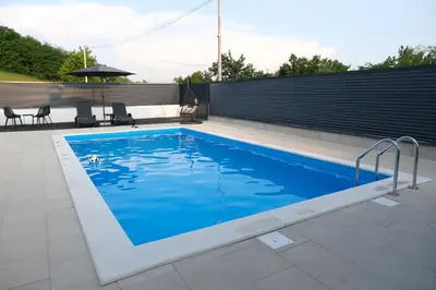 a swimming pool with blue water in a backyard at Luxury Villa JAKOV in Banja Luka