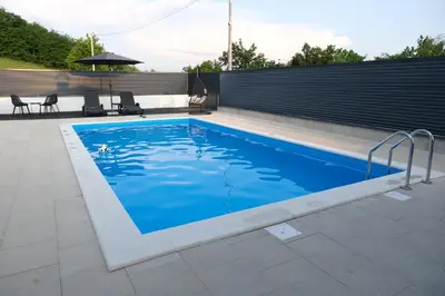 a swimming pool with blue water in a backyard at Luxury Villa JAKOV in Banja Luka