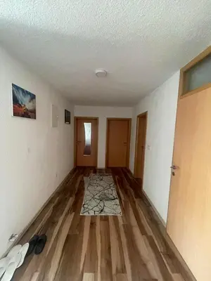 an empty living room with wooden floors and white walls at Porodični mir in Bugojno