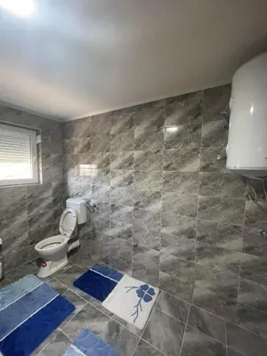 a bathroom with a toilet and a tiled wall at Porodični mir in Bugojno