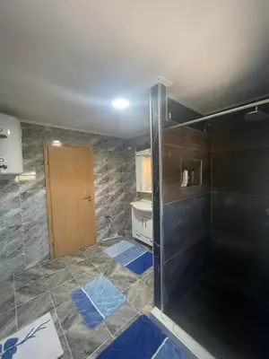 a bathroom with a shower and blue tiles on the floor at Porodični mir in Bugojno